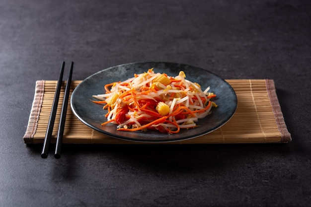 Ensalada de repollo chino saludable en placa sobre fondo negro