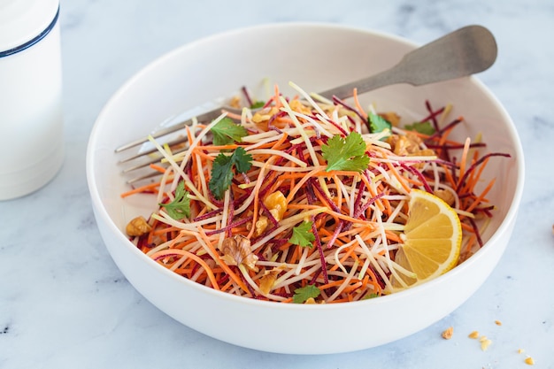 Ensalada de repollo de remolacha de zanahorias de primavera con nueces y hierbas en un tazón blanco