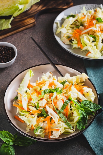 Ensalada de repollo con zanahorias frescas y albahaca en un plato vista vertical