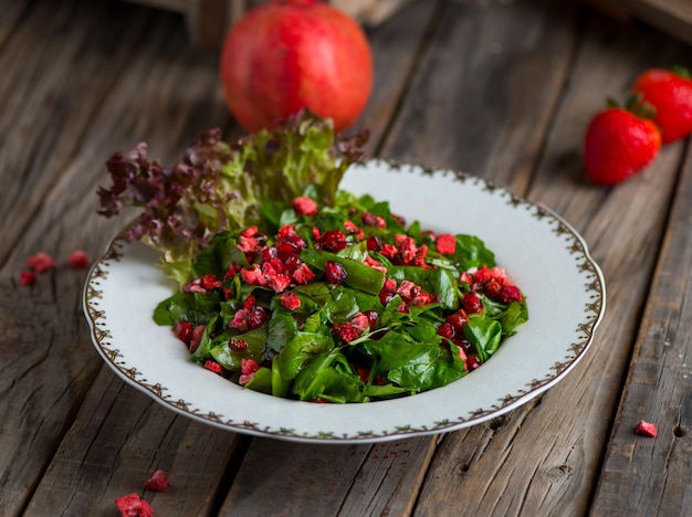 Ensalada Rocca con salsa de fresa y granada servida en un plato aislado en una vista lateral de fondo de madera