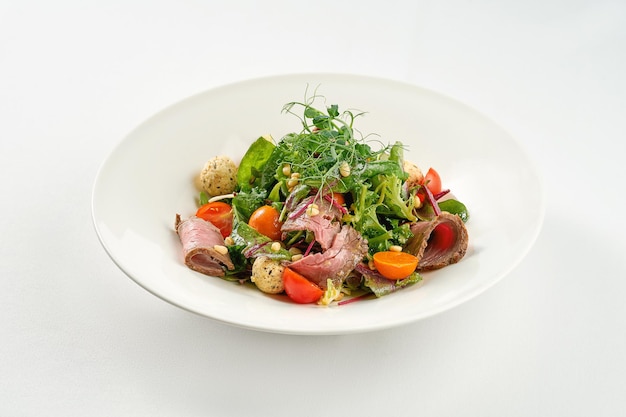 Ensalada de rosbif y piñones en un plato blanco.