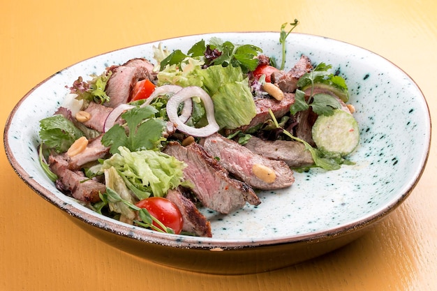 Ensalada con rosbif y tomates cherry sobre un fondo de madera