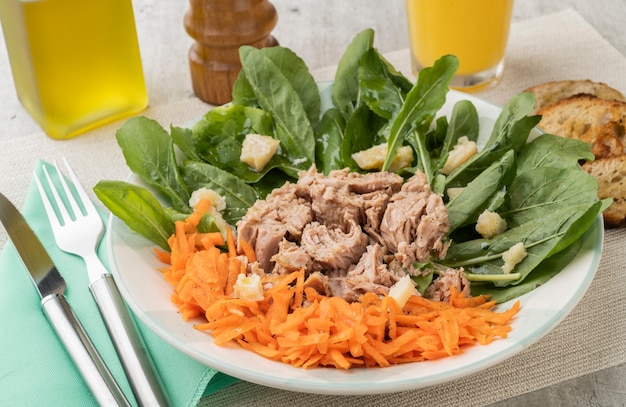 Ensalada de rúcula, atún, parmesano y zanahoria con aceite de oliva y zumo de naranja.