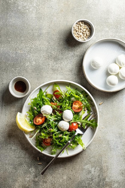 Ensalada con rúcula de cereza mozzarella y semillas en un plato con limón