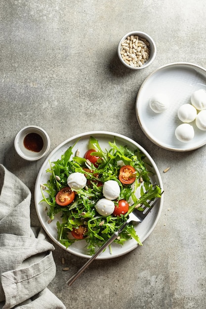 Ensalada con rúcula de cereza mozzarella y semillas con salsa y vista superior de fondo texturizado de servilleta