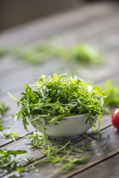 Ensalada de rúcula fresca en un plato blanco sobre la mesa de madera.