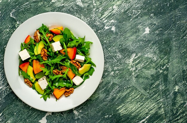 Ensalada de rúcula, queso, remolacha, nuez, en el fondo de pizarra, piedra u hormigón.