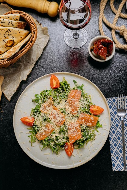 ensalada de rúcula con salmón ahumado tomates cereza y parmesán recién rallado servido con vino tinto