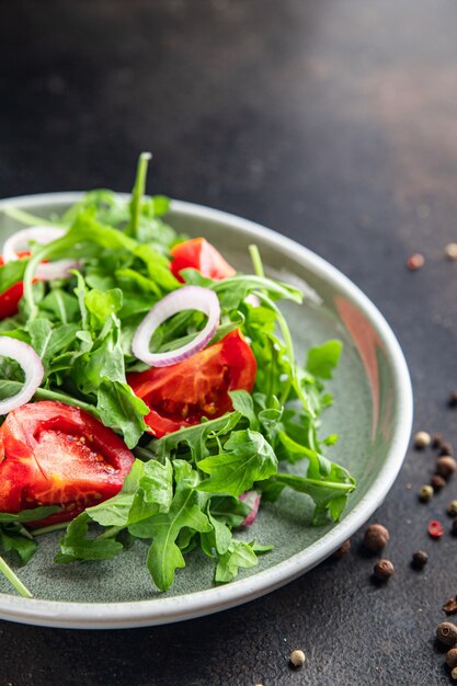 Ensalada de rúcula y tomate vegetal en un plato porción fresca listo para comer bocadillo en la mesa