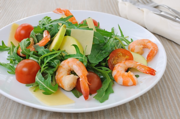 Ensalada de rúcula y tomates cherry con camarones, rodajas de manzana y parmesano