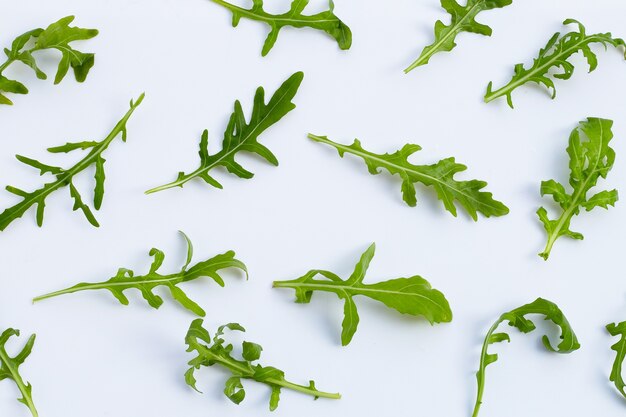 Ensalada de rúcula verde fresca sobre fondo blanco.