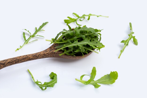 Ensalada de rúcula verde fresca sobre superficie blanca.