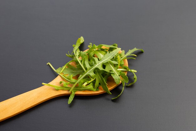 Ensalada de rúcula verde fresca sobre superficie oscura.