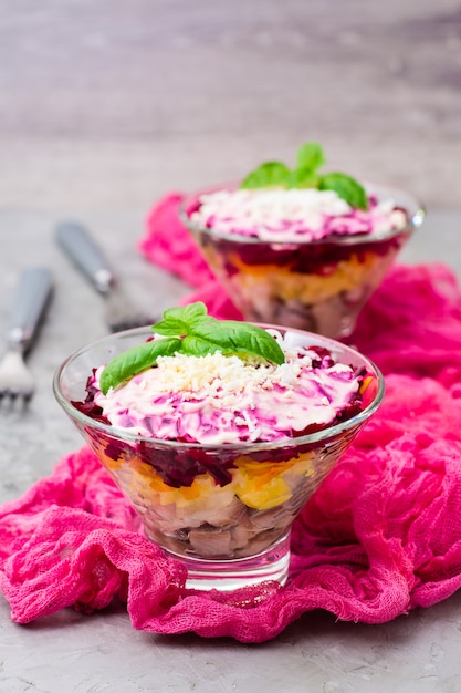 Ensalada rusa tradicional de verduras y pescado hervido, arenque bajo un abrigo de piel en cuencos sobre la mesa