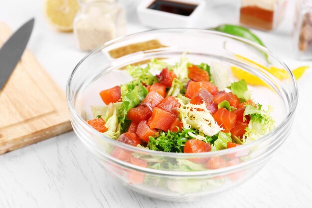 Ensalada sabrosa en plato de vidrio sobre fondo de mesa de madera de color