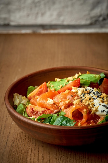 Ensalada con salmón ligeramente salado y huevo escalfado en un plato sobre un fondo de madera