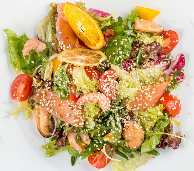 Ensalada con salmón y marisco sobre un fondo blanco.