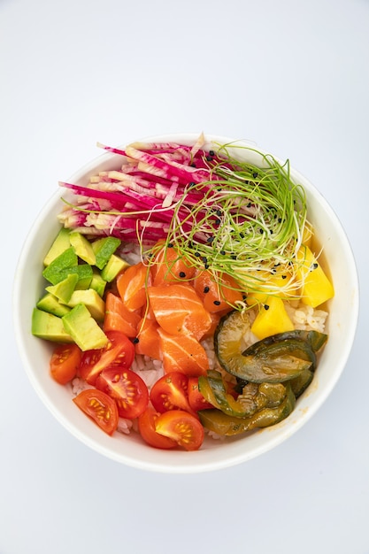 Ensalada de salmón, tomates en un plato blanco sobre un fondo blanco.