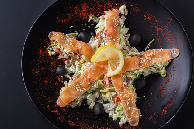 Ensalada de salmón, verduras y limón en un plato negro