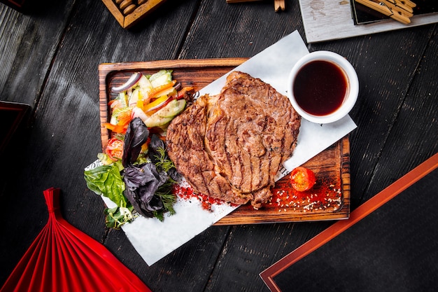 Ensalada de salsa de carne jugosa a la parrilla sobre tabla de madera