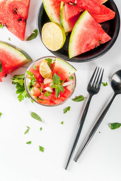 Ensalada de salsa de verduras con sandía, tomates, cebollas, verduras, lima en porciones de vidrio