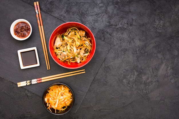 Foto ensalada; salsas y fideos servidos en un bol con palillos.