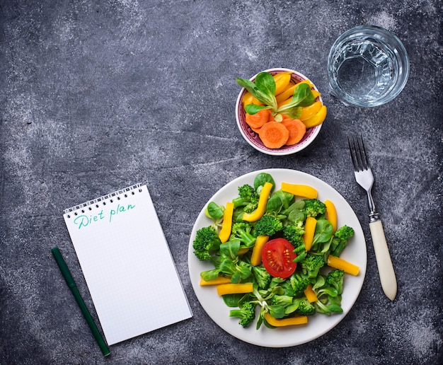 Ensalada saludable, agua limpia y cinta métrica.