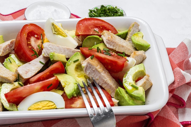 Ensalada saludable de huevo, pollo, aguacate y tomate con aceite de oliva