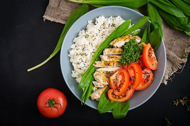 Ensalada saludable con pollo, tomates, ajo silvestre y arroz. Nutrición apropiada.