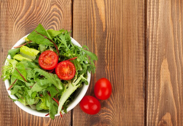 Ensalada saludable con tomates en mesa de madera