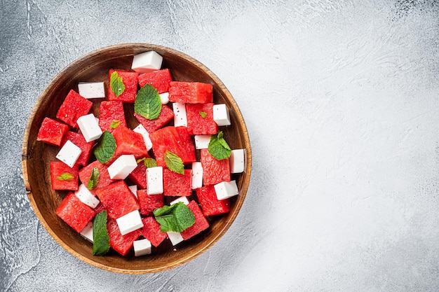 Ensalada de sandía con queso feta en un plato de madera. Fondo blanco. Vista superior. Copie el espacio.