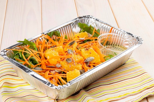 Ensalada con semillas de calabaza naranja y jugo fresco en recipientes sobre un fondo blanco Dieta para llevar y comida saludable