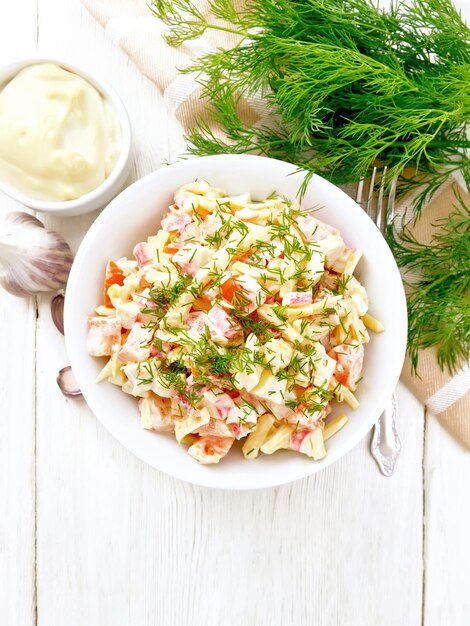 Ensalada de surimi y huevos con mayonesa sobre tablero ligero