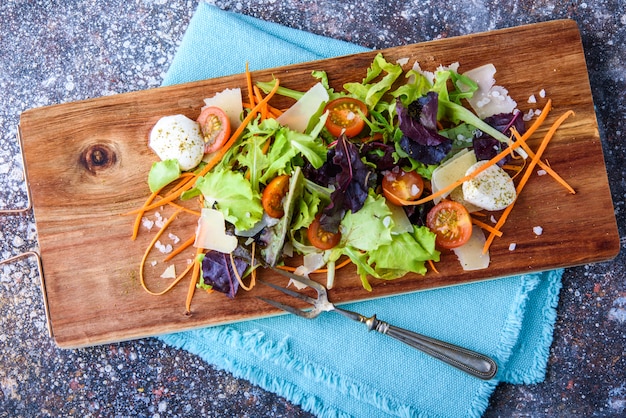 Ensalada en una tabla de madera con una servilleta.