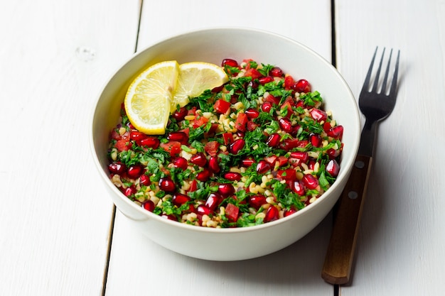 Ensalada tabulé con bulgur, menta, perejil, tomate y granada. Alimentación saludable. Comida vegetariana.