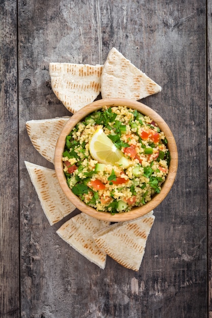 Ensalada tabulé con cuscús y pan de pita en una mesa rústica