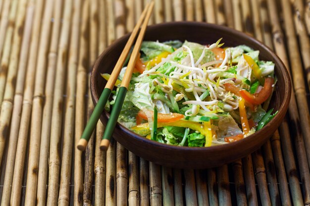 Ensalada tailandesa con verduras y brotes en una mesa de bambú