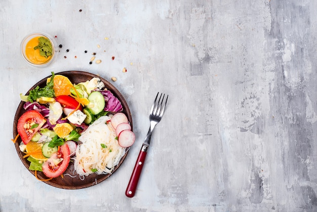 Ensalada de los tallarines del hilo de la haba con el pepino y la zanahoria, ensalada vegetariana en una placa en el fondo de piedra