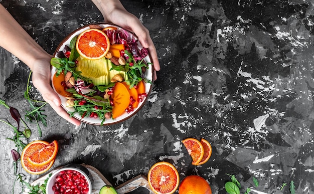 Ensalada de tazón de buda vegetariana saludable con aguacate, caqui, naranja sanguina, nueces, espinacas, rúcula y granada sobre un fondo claro Vista superior de formato de banner largo