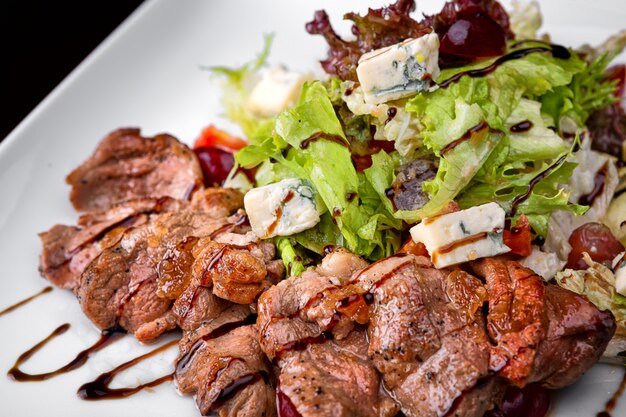 Ensalada templada con carne y queso en un plato blanco