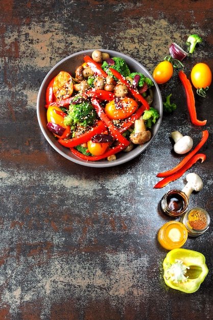 Ensalada tibia con brócoli, champiñones y pimentón rojo. Tazón vegano con verduras calientes sobre un elegante fondo cutre. Comida sana. Almuerzo de fitness con champiñones y verduras.