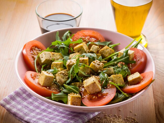 Ensalada con tofu tomates rúcula y semillas de sésamo