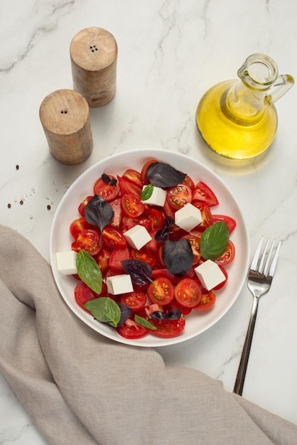 Ensalada con tomate feta y albahaca sobre un fondo gris