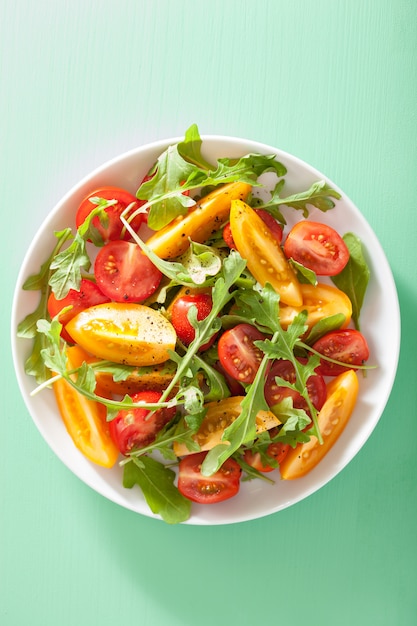 Ensalada de tomate con rúcula sobre fondo verde