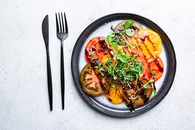 Ensalada de tomates frescos y coloridos con vinagre balsámico en una vista superior del plato