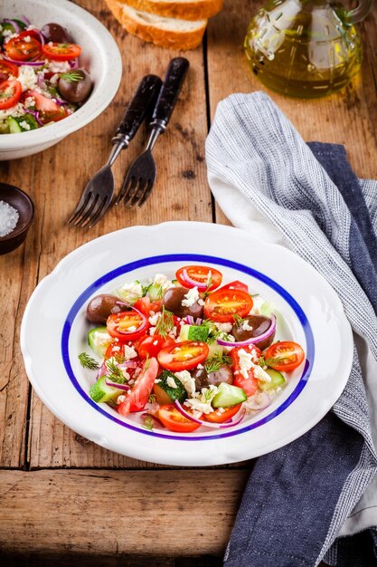 Ensalada con tomates pepinos aceitunas cebollas queso feta y cuscús en mesa de madera