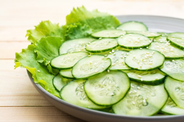 Ensalada tradicional de rodajas de pepino y semillas de sésamo en un plato sobre una mesa de madera