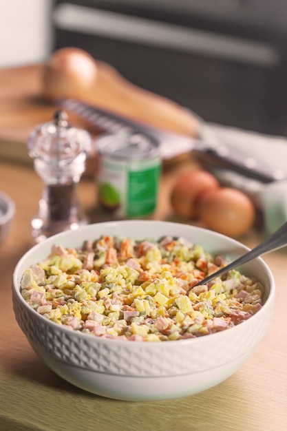 Ensalada tradicional rusa Olivier con guisantes sobre fondo de madera en la cocina