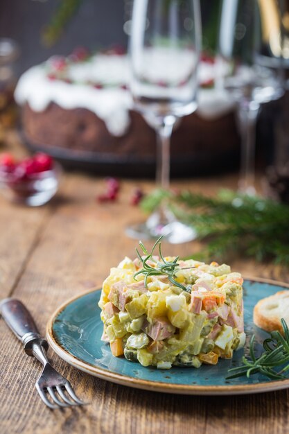 Ensalada tradicional rusa con verduras cocidas con mayonesa en un plato de madera