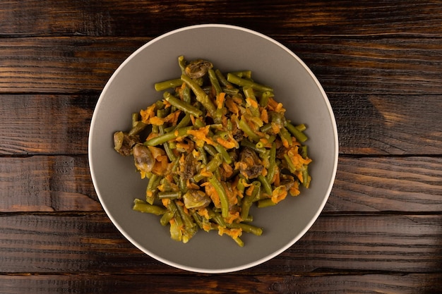 Ensalada con trozos de pollo y espárragos en un plato sobre un fondo de madera oscura.